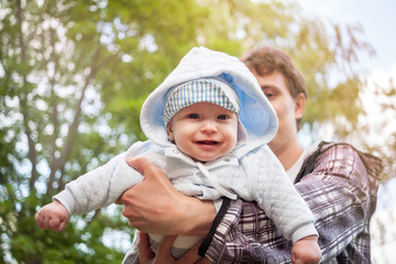 little baby in father's arms against sunny sky , father's day, fatherhood, happy baby, sunny child