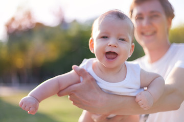 little baby in father's arms against sunny sky , father's day, fatherhood, happy baby, sunny child