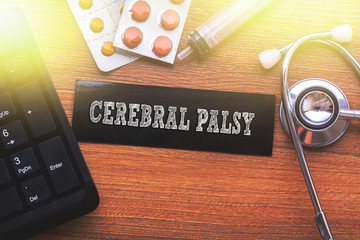 CEREBRAL PALSY words written on label tag with medicine,syringe,keyboard and stethoscope with wood...