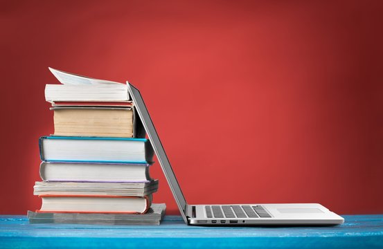 Stack of books with laptop on table