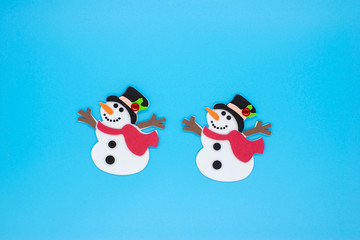 Funny snowmen in red and green scarves and black hats on a blue background