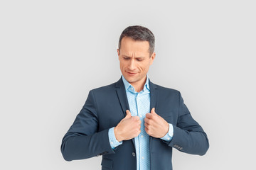 Freestyle. Mature businessman standing isolated on white putting on blazer preparation smiling confident