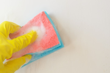 Hand in yellow protective glove washes with a sponge with a cleaning solution light surface.Regular home cleaning.Copyspace.