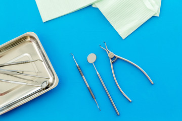 Stomatological tools in tray on dentist's desk on blue background top-down