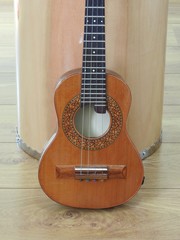 Obraz premium Close-up of a Brazilian stringed musical instrument, the cavaquinho, leaning against a drum, on a wooden surface. This instrument is widely used to accompany samba and choro, popular Brazilian rhythms