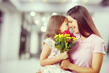 Mother and daughter with bouquet of flowers on blurred background.