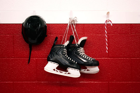 Christmas Background Of Hockey Skates With Candy Cane Hanging Over Red Wall With Copy Space 