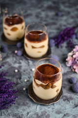 Homemade coffee flavoured layered Italian mascarpone cheese Tiramisu dessert topped with cocoa in glasses