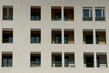 gray wall of a large house with rows of windows and balconies