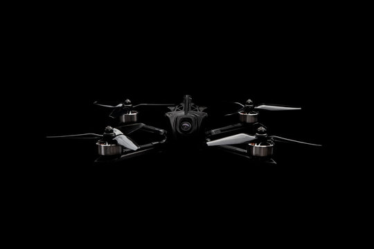 Modern FPV drone on a black background. Four-engine aircraft on the radio control. Drone for racing, filming and entertainment.