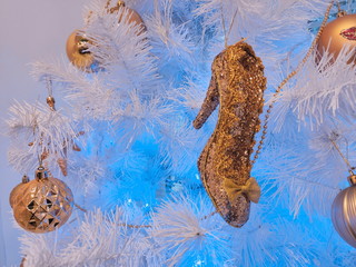 Christmas tree toy golden slipper Cinderella hanging on the snow-covered branches of an artificial spruce on a blue background. Background for New Year greetings.