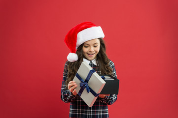 little girl open present box. happy new year gift. time for christmas holiday presents. small girl in santa hat. cheerful child red background. christmas kid shopping. best gift for xmas