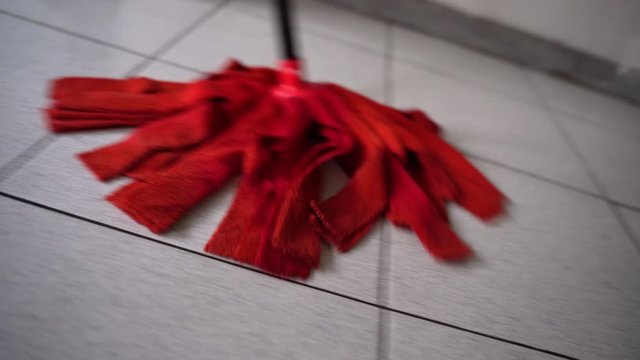 Close-up of mopping floor, cinematic frame of moving mop on wet floor. Maid washing dirty floor, cleanness and hygiene at home or office room. Mopping floor and clean-up concept