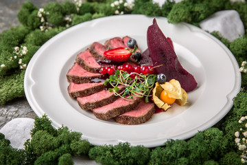 Beef medallions with sweet drunk pear in wine sauce, strawberries, currants and micro greens. Banquet festive dishes. Fine dining restaurant menu. Eco life style healthy eating 
