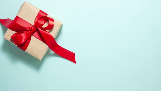 Gift box with a red ribbon bow are in the frame on blue background. Valentines day concept. Flat lay top view stop motion animation with space for text