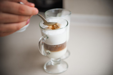 The hands of a young man make coffee from a coffee machine. Morning latte for breakfast at home. Homemade barista cappuccino in a stylish kitchen. Close up, place for text, copy space