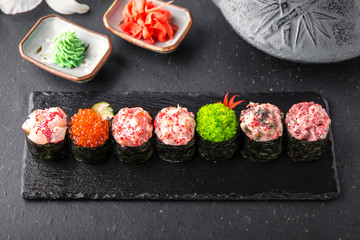 Gunkan sushi set with salmon, tuna, perch, eel, scallop, caviar, shrimp, sharp.  Traditional Japanese cuisine. Black background. Beautiful geometric style food
