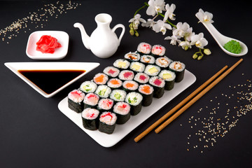 Sushi menu. Japanese food. Set of maki with salmon, tuna, chuka, cucumber, avocado, cheese, eel, shrimp, crab stick, tobiko caviar. Black background. Beautiful geometric food style.