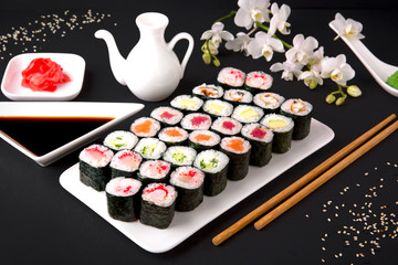 Sushi menu. Japanese food. Set of maki with salmon, tuna, chuka, cucumber, avocado, cheese, eel, shrimp, crab stick, tobiko caviar. Black background. Beautiful geometric food style.