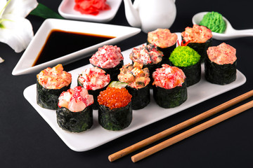 Gunkan sushi set with salmon, tuna, perch, eel, scallop, caviar, shrimp, sharp.  Traditional Japanese cuisine. Black background. Beautiful geometric style food