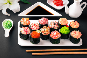 Gunkan sushi set with salmon, tuna, perch, eel, scallop, caviar, shrimp, sharp.  Traditional Japanese cuisine. Black background. Beautiful geometric style food