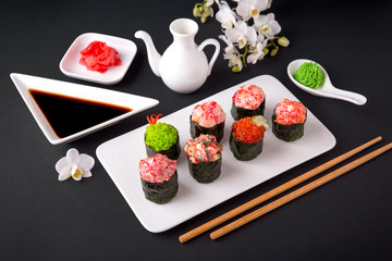 Gunkan sushi set with salmon, tuna, perch, eel, scallop, caviar, shrimp, sharp.  Traditional Japanese cuisine. Black background. Beautiful geometric style food