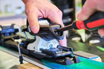 Adjusting a ski binding rear piece release tension spring, using a flathead screwdriver - close up...