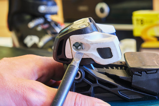 Adjusting DIN value (release setting) of a ski binding front (toe) piece using a flathead screwdriver - side view.