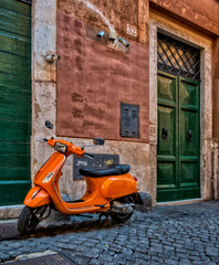 Fototapeta premium A pic of an orange scooter parked outside a door