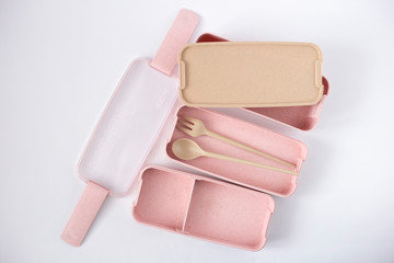 Pink lunch box made from wheat straw on a white background. Biodegradable three-compartment lunch box with spoon and fork. Zero waste concept