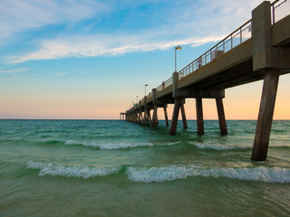 Pensacola beach with turquoise waters waves and pier entering into gulf of Mexico