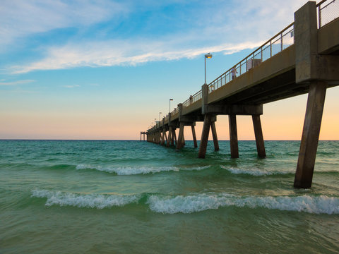 Fototapeta Pensacola beach with turquoise waters waves and pier entering into gulf of Mexico