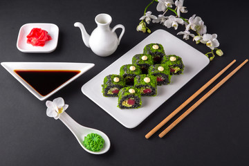 Fototapeta premium California Sushi Roll Green Dragon with made of Fresh Tuna, Avocado and Cream Cheese with black rice with cuttlefish ink inside and tobiko caviar. Traditional Japanese cuisine. Asian food