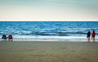 Older and younger couple watching the ocean at beach in Florida.