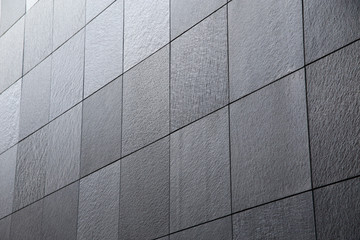 Abstract modern architecture and construction or finishing material background of tiled granite wall. Minimalist building exterior or interior with geometric structure viewed in diagonal perspective.