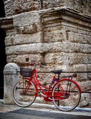 A beautiful old fashioned red bicycle with front basket locked on a metal railing 