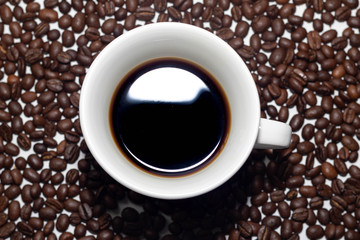 cup with very strong coffee and with the coffee beans making the composition and the background of the photo.