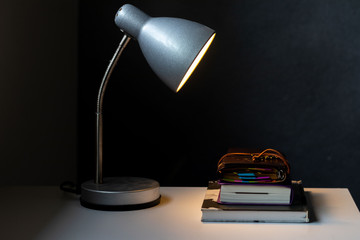 Office lamp illuminating the books with a dark gray background.