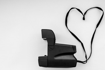 side view instant photo camera with strap in heart - copy space b&w