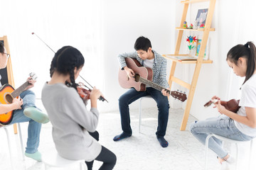 blurred asian children group playing music with acoustic musical instrument, they feeling fun and...