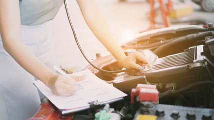 Closeup of Inspection worker writing on a clipboard In the garage before delivering the customer car.