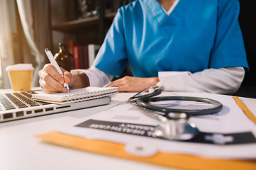 Medical technology concept. Doctor working with mobile phone and stethoscope and digital tablet laptop in modern office at hospital in morning light