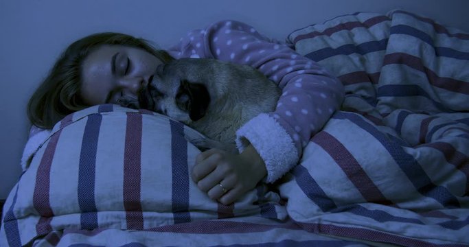 Adorable teen girl and her pug dog in the bed are sleeping together.  Friendship with pet concept. Together forever, inseparable friends
