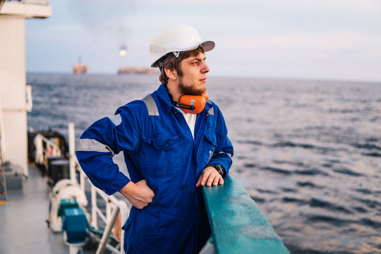Marine Deck Officer or Chief mate on deck of offshore vessel or ship , wearing PPE personal protective equipment - helmet, coverall. Sea view
