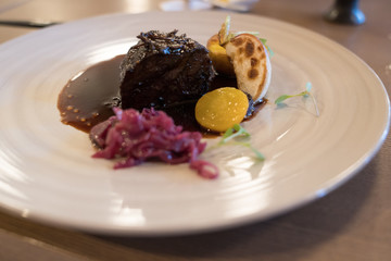 tender roast beef dinner plated with pickled radish and yellow tomato