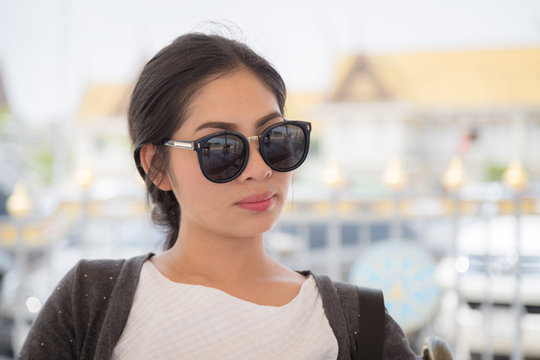 Portrait of a beautiful young asian woman wearing sunglasses in the park with bokeh background