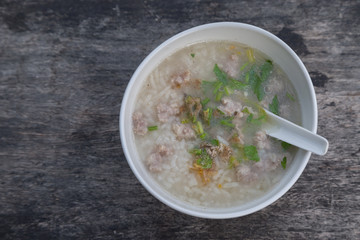 Pork porridge in a white cup on wooden table