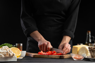 The chef cuts cherry tomatoes to prepare a tasty and fresh salad. Vegetarian and fresh food,...