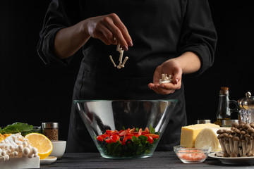 Chef sprinkles mazzarella cheese in a bowl with salad,. Freeze in motion, Salad, organic ingredients and products. Vegetarian and tasty food. Advertising photo of food