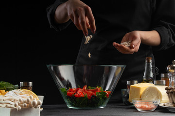 A professional chef cooks a fresh and healthy Italian salad, rubbing mazarella cheese, freezing in motion. Organic and wholesome food. Healthy nutrition and vitamins. Vegetarian, with space